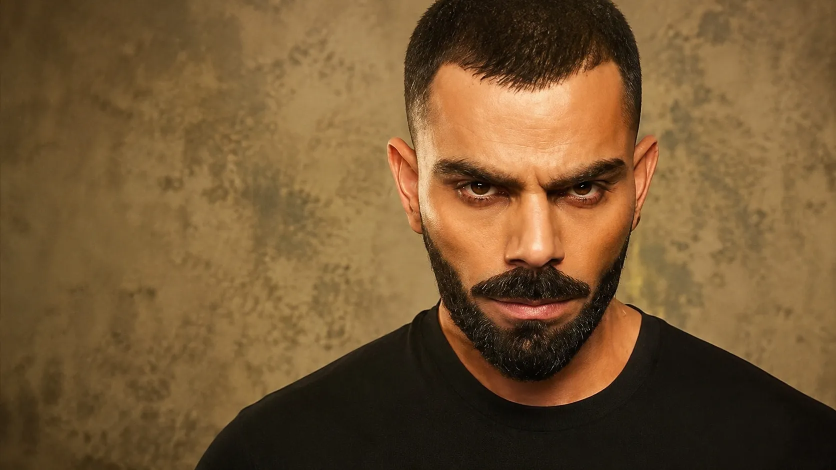 An Indian man featuring a low-maintenance buzz cut hairstyle with a clean low fade and a well-groomed short beard.