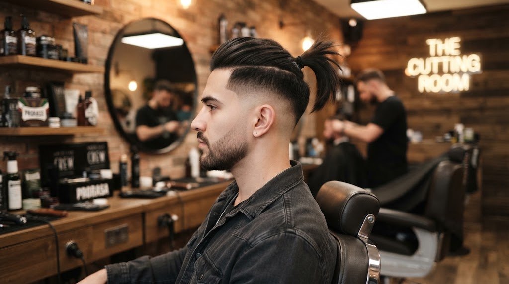 Side-profile portrait of a stylish man showing an undercut tail hairstyle with shaved sides and a sharp high tail in a modern barbershop.